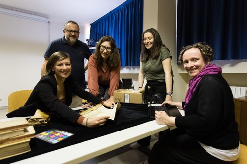 Five smiling researchers around a table working on a manuscript.