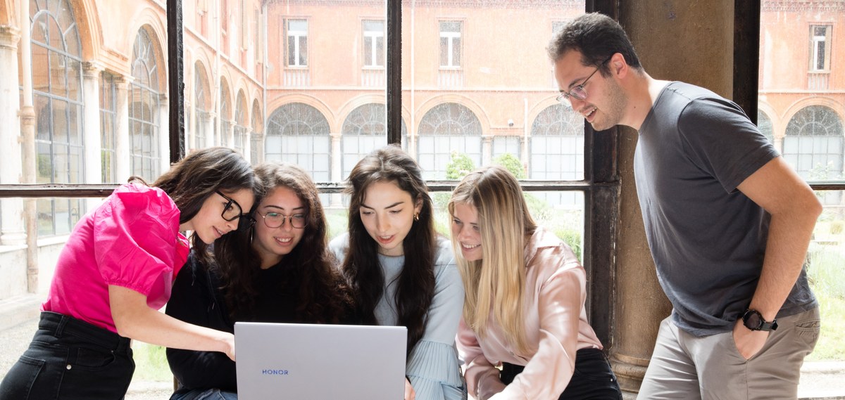 Quattro studentesse e uno studente cercano informazioni davanti a un laptop.